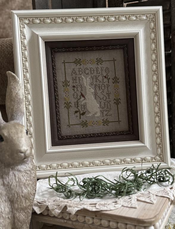 Framed bunny cross-stitch sampler with tulip and olive border