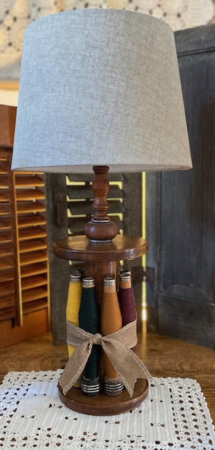 Accent lamp built from a large antique spool ringed by seven threaded spools