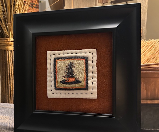 Framed punch needle witch hat hand stitched to rusty orange wool